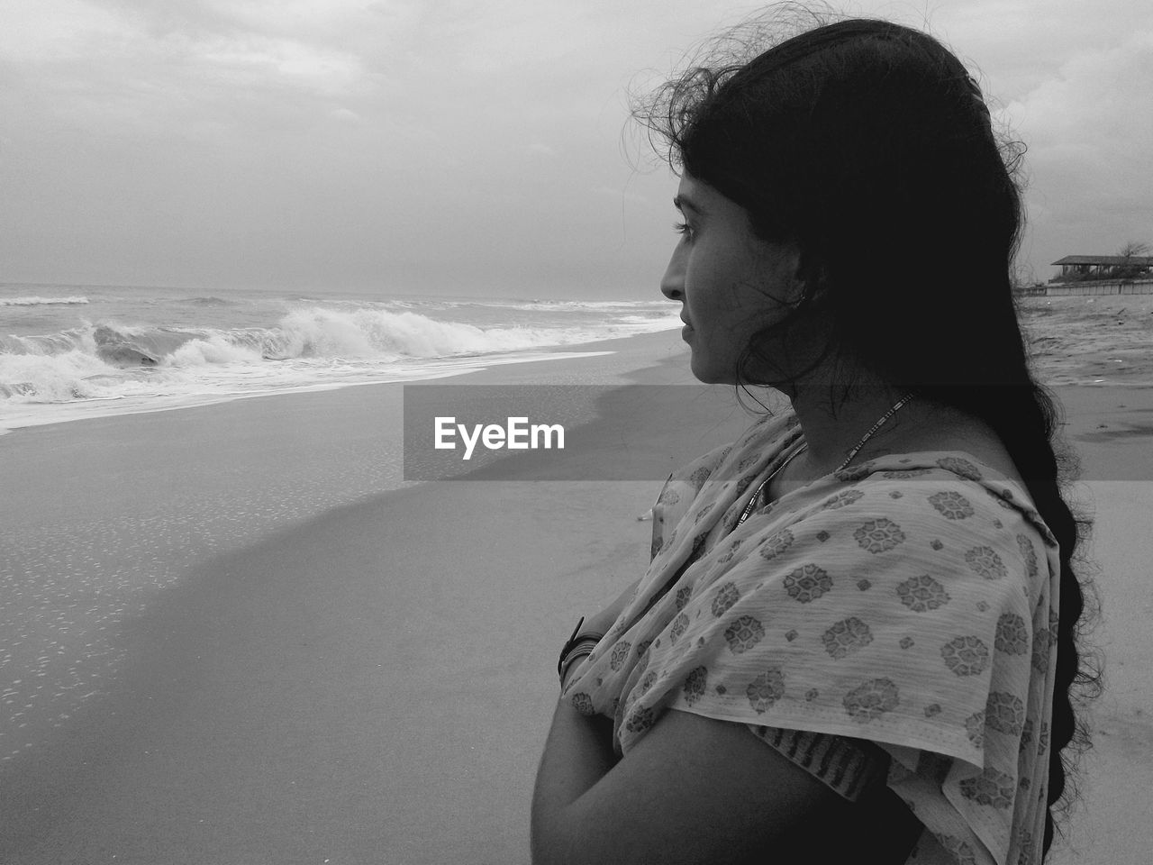 Side view of thoughtful woman standing on shore at beach