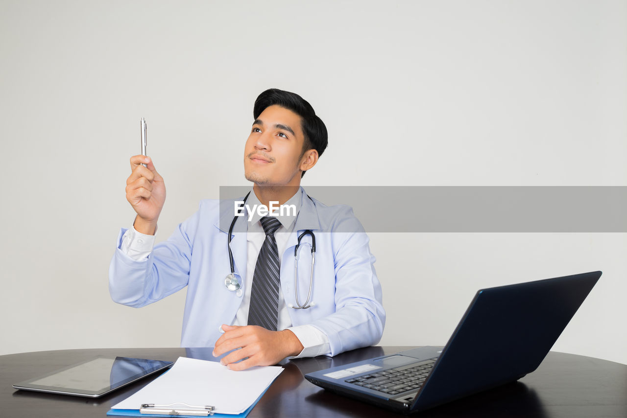 Doctor pointing up while sitting at desk in hospital