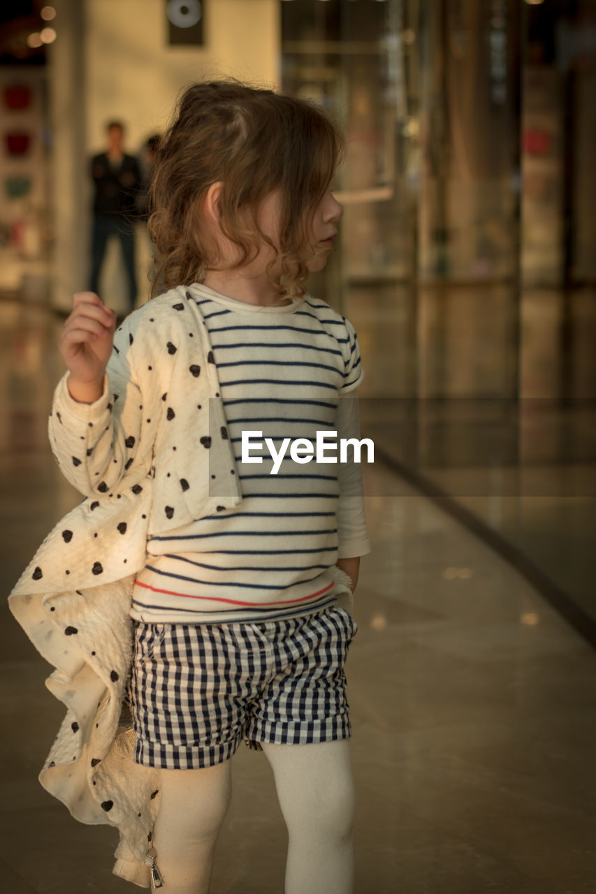 Cute girl looking away while standing on floor
