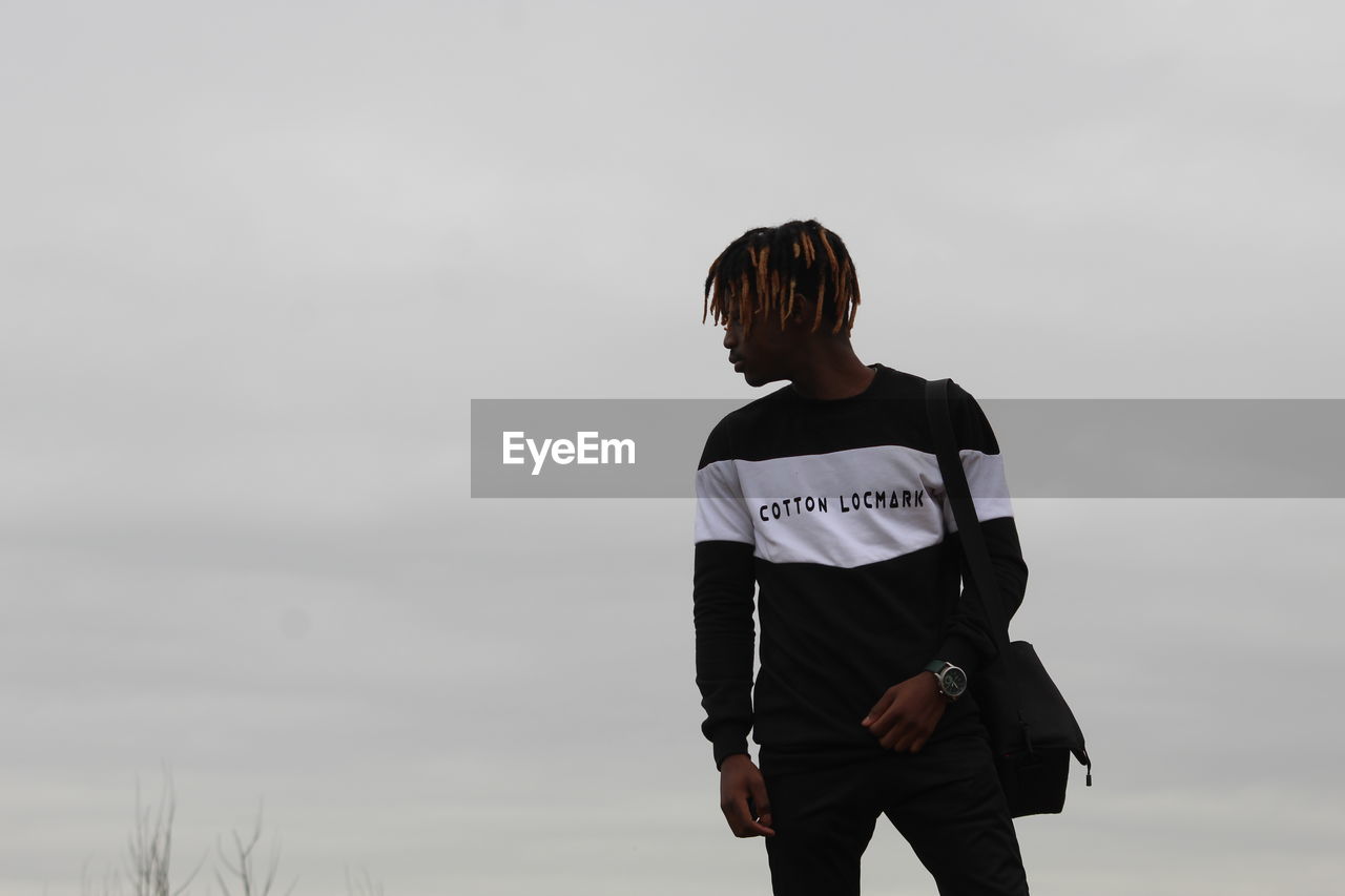 REAR VIEW OF YOUNG MAN LOOKING AT SKY