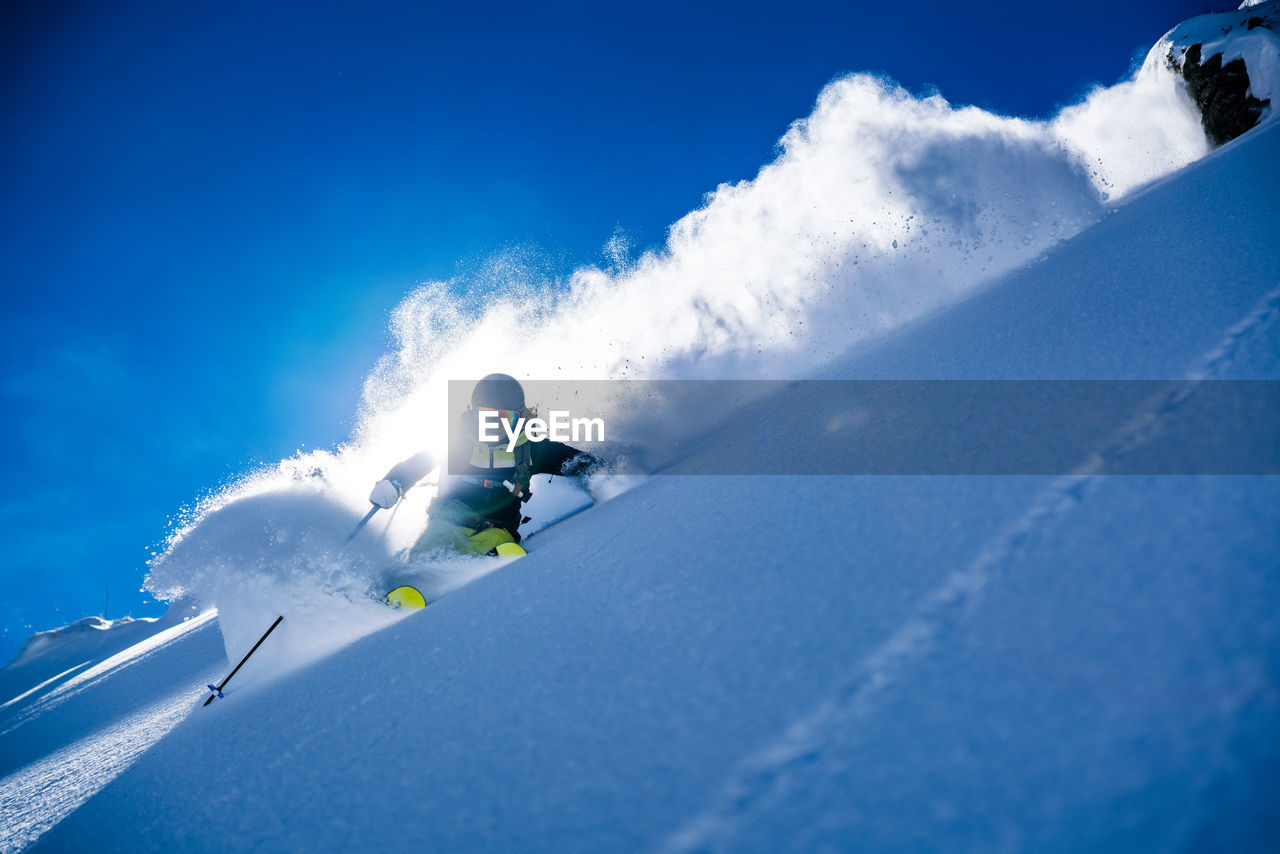 Woman skiing on snowcapped mountain against sky