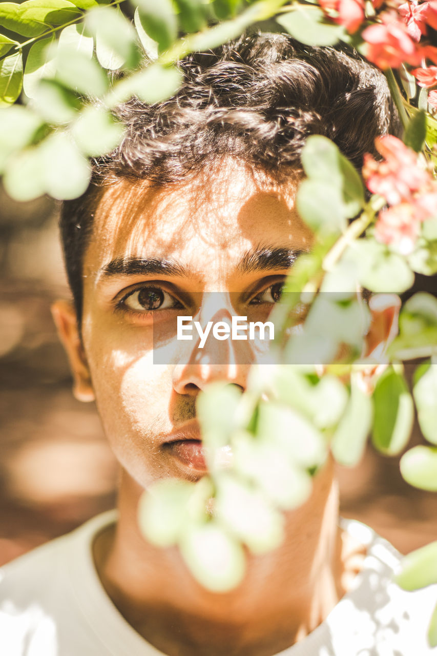 Close-up portrait of young man standing amidst plants at park