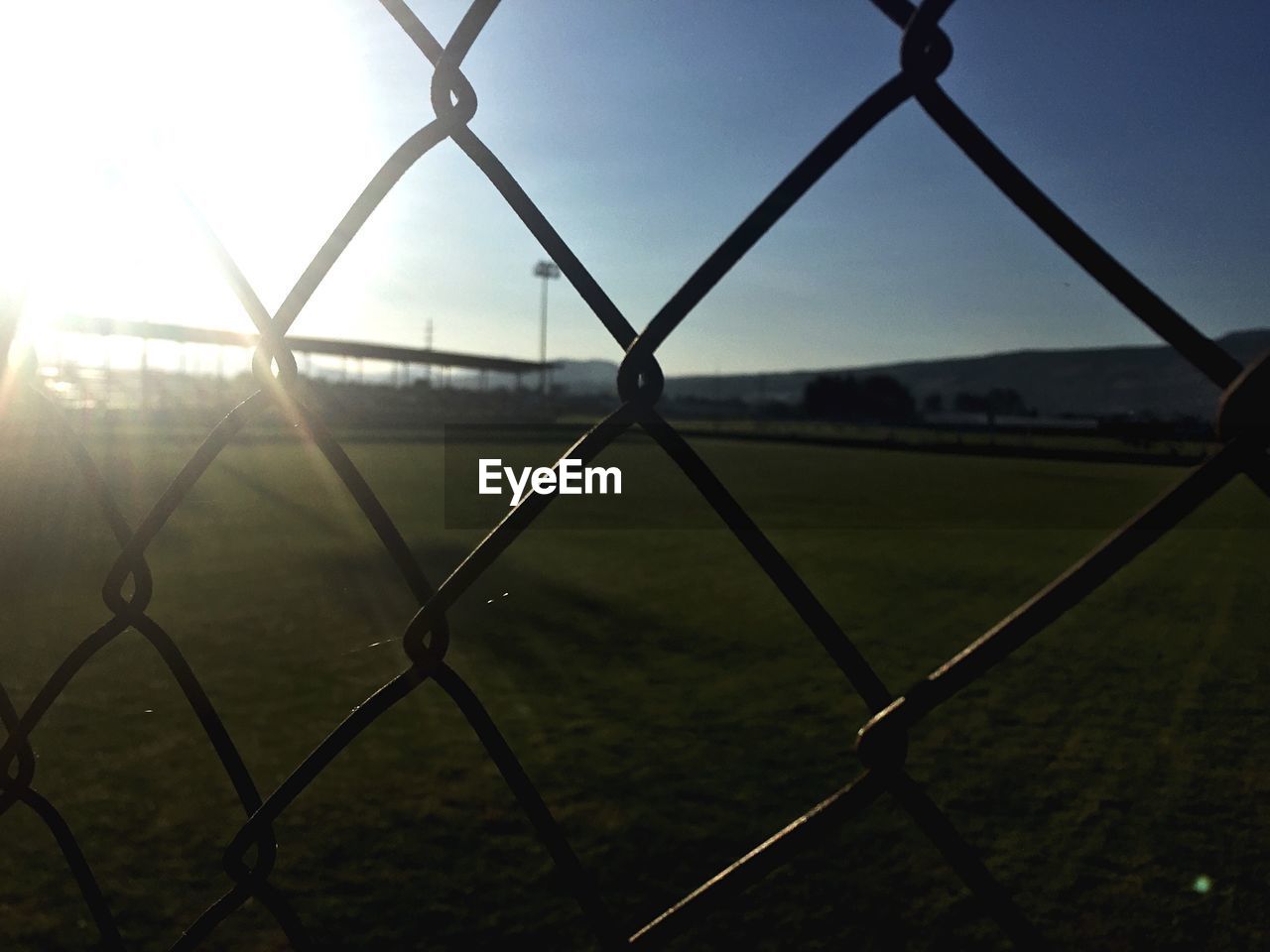 Scenic view of grassy landscape seen through chainlink fence