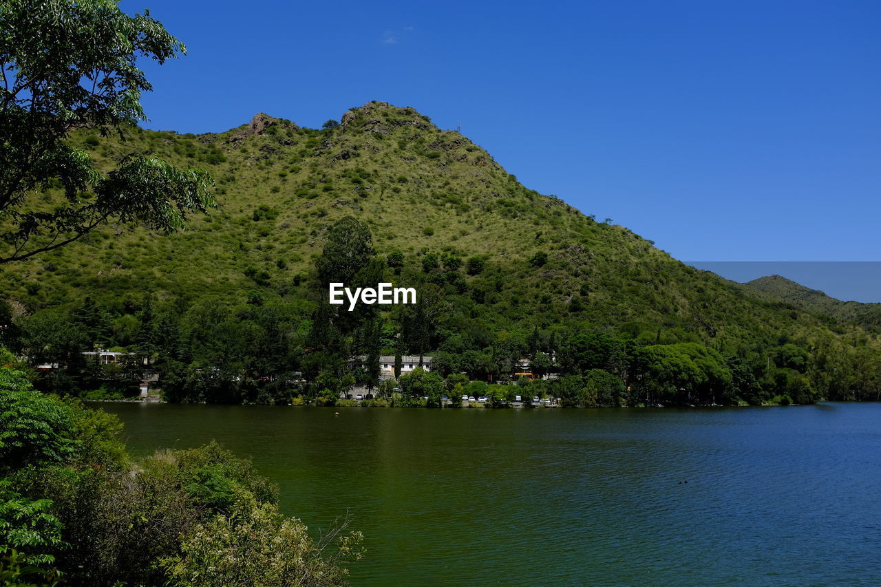 Scenic view of lake and trees against clear blue sky