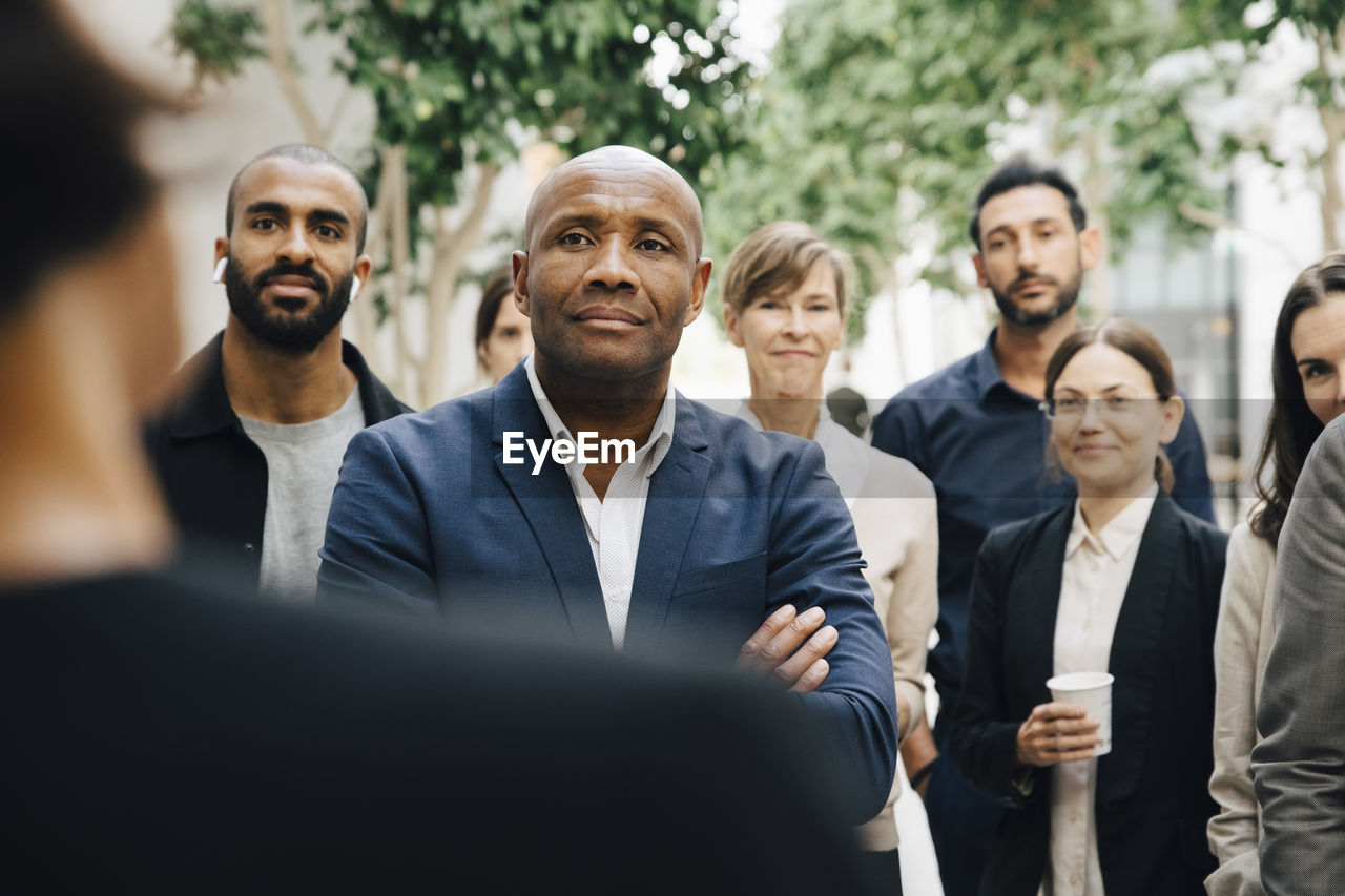 Smiling colleagues listening to female entrepreneur in seminar outside office