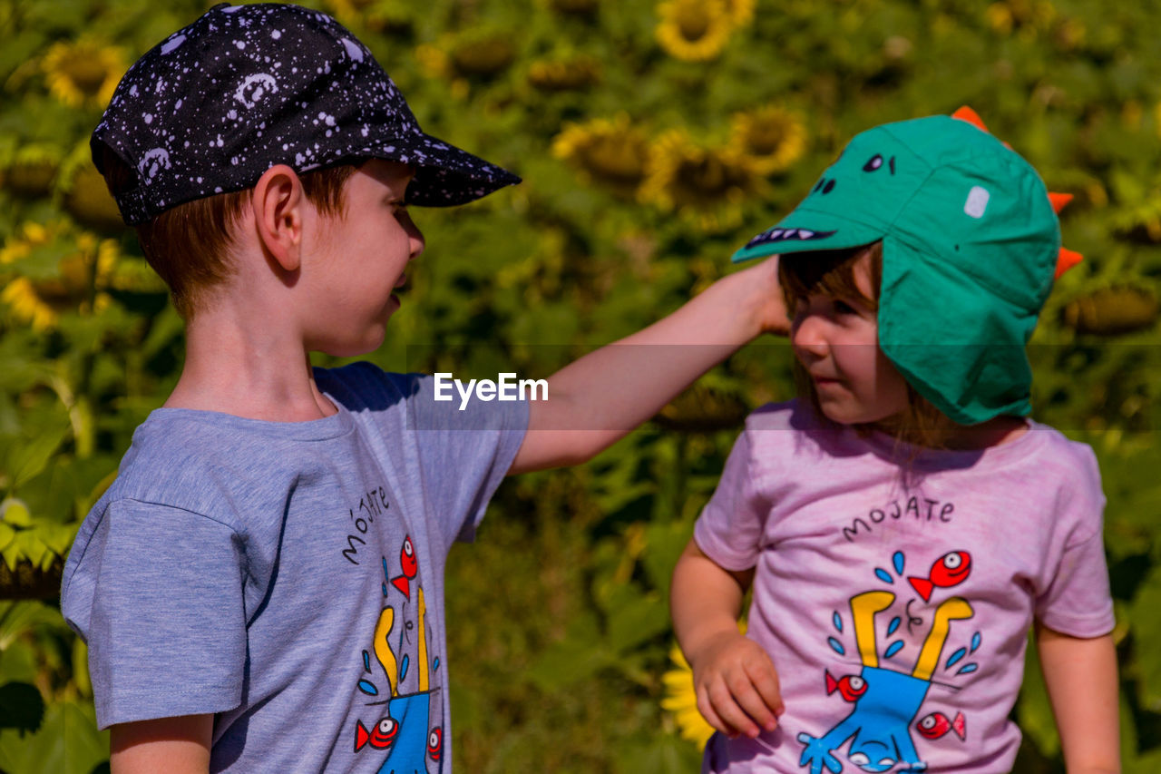 Boy and girl with baseball caps sitting outdoors 