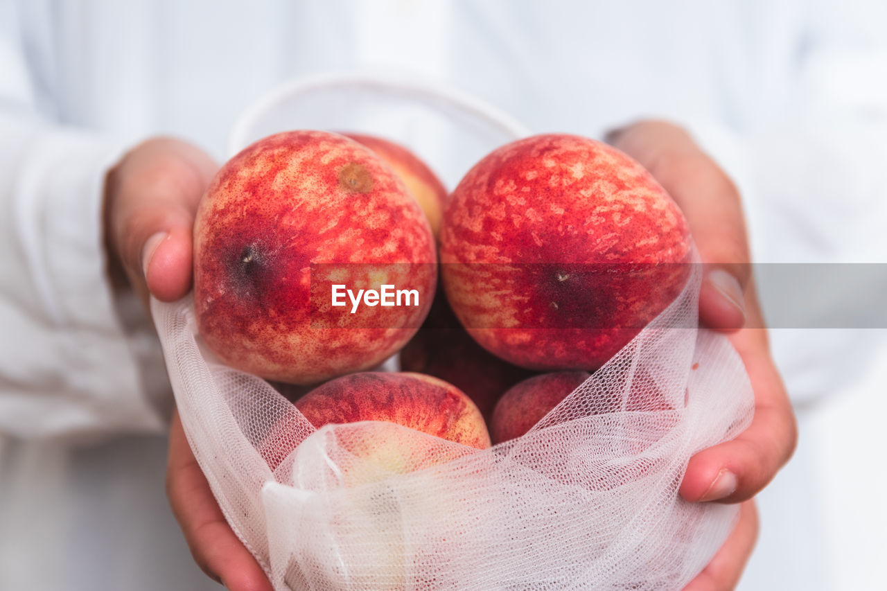 Close-up of hand holding fresh fruit in sustainable ecofriendly mesh bag