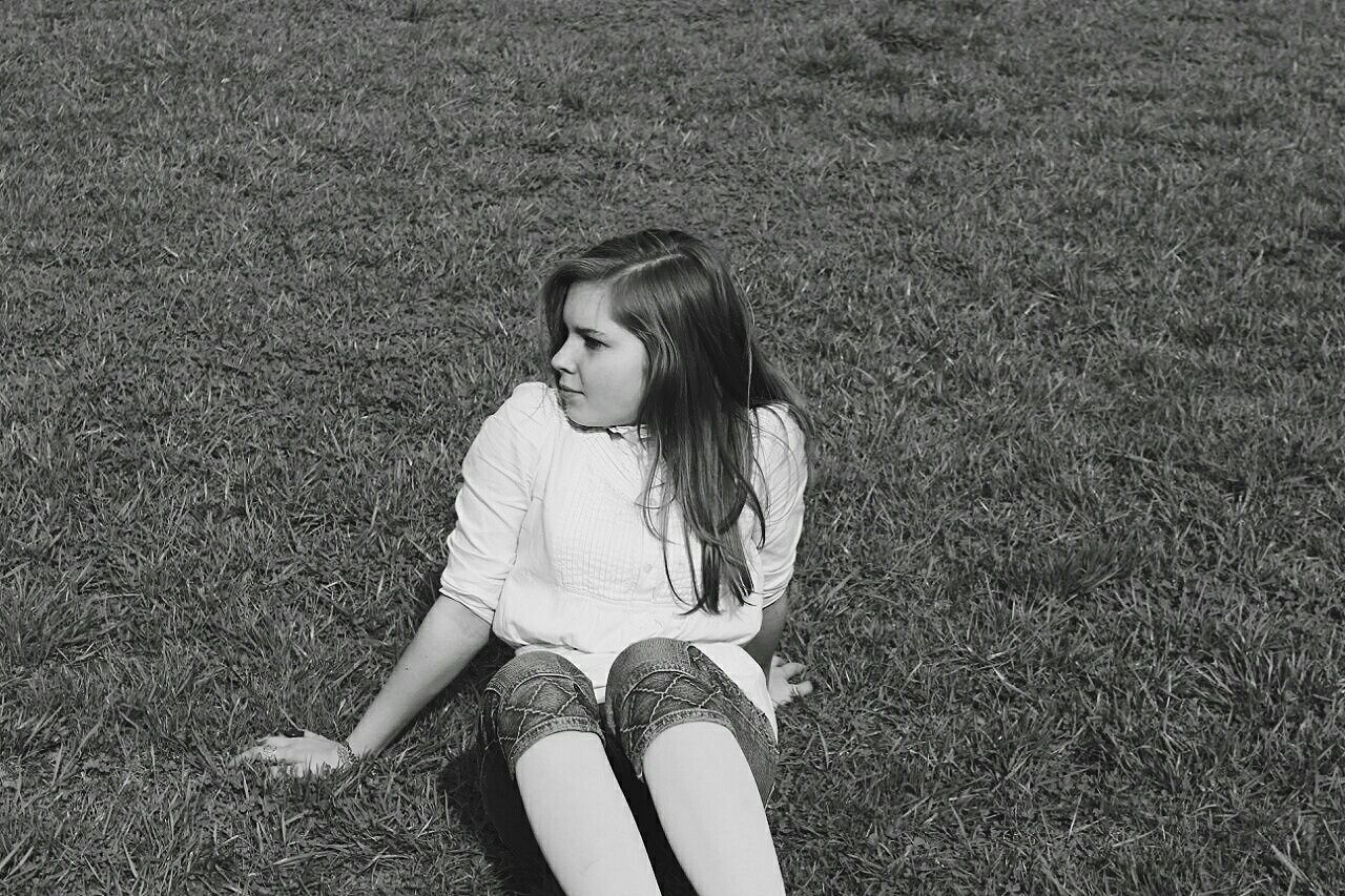 High angle view of woman sitting on grassy field at park