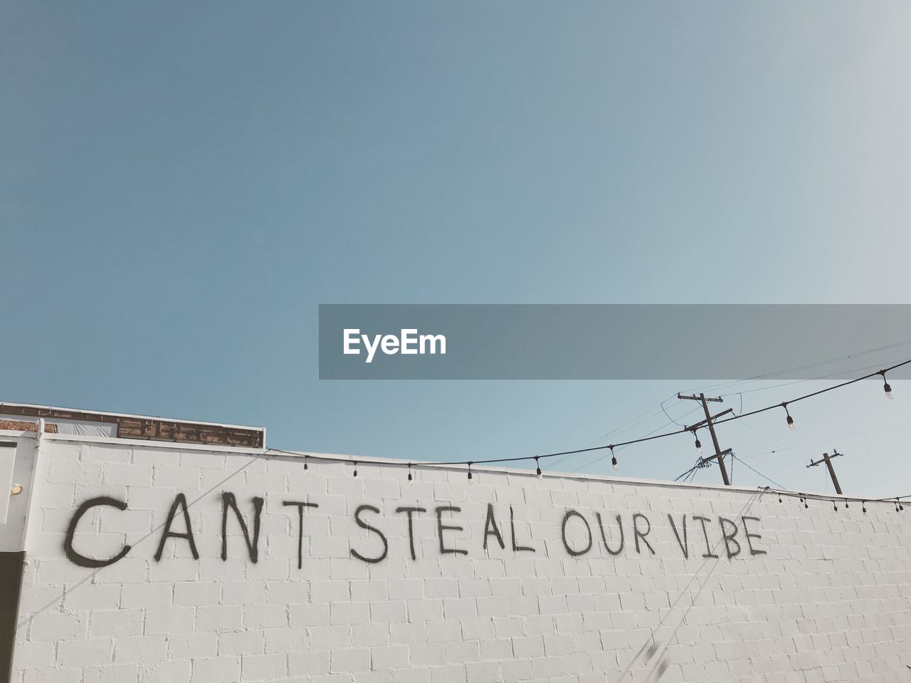 Low angle view of text on wall against clear sky