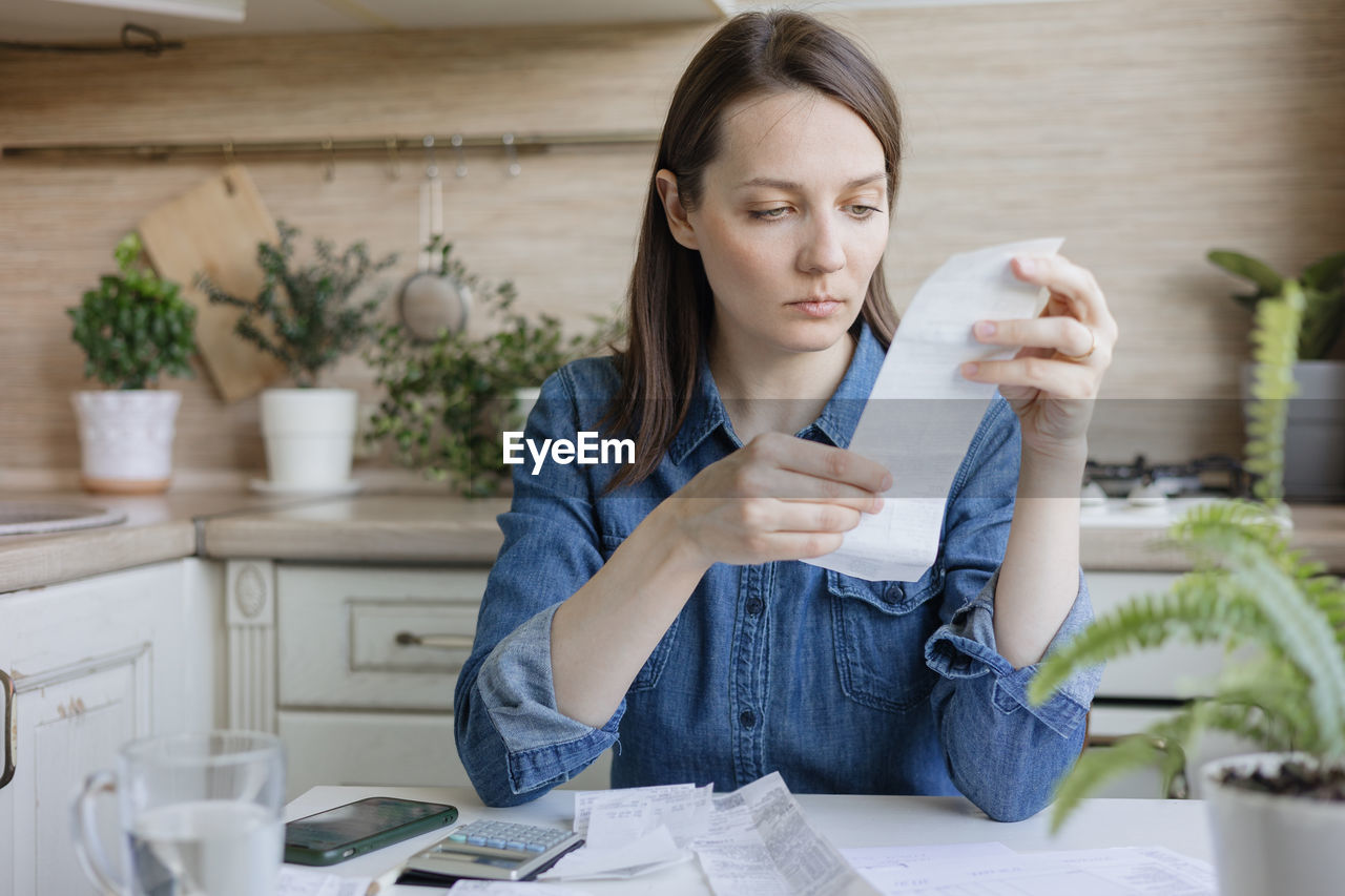 portrait of young woman using mobile phone while sitting on table