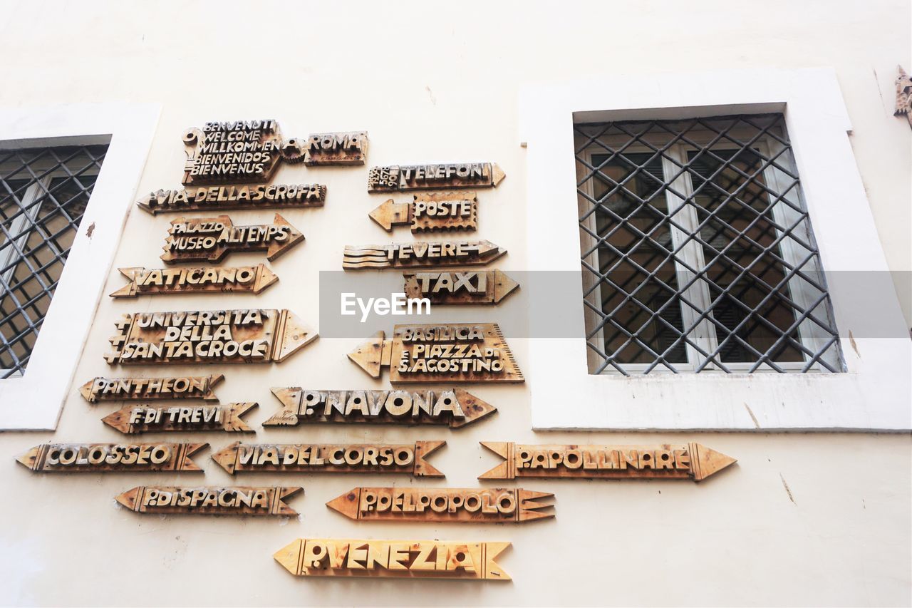 Low angle view of directional signs mounted on house wall