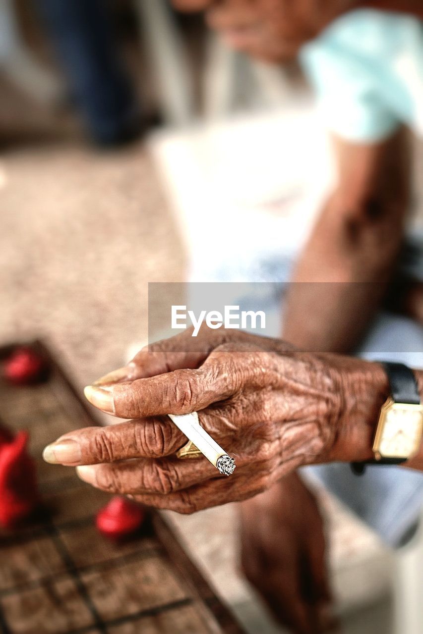 CLOSE-UP OF HAND HOLDING CIGARETTE