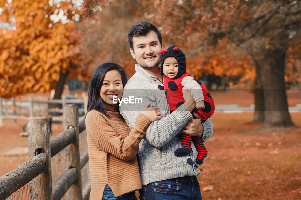 Portrait of parents with cute daughter in park during autumn