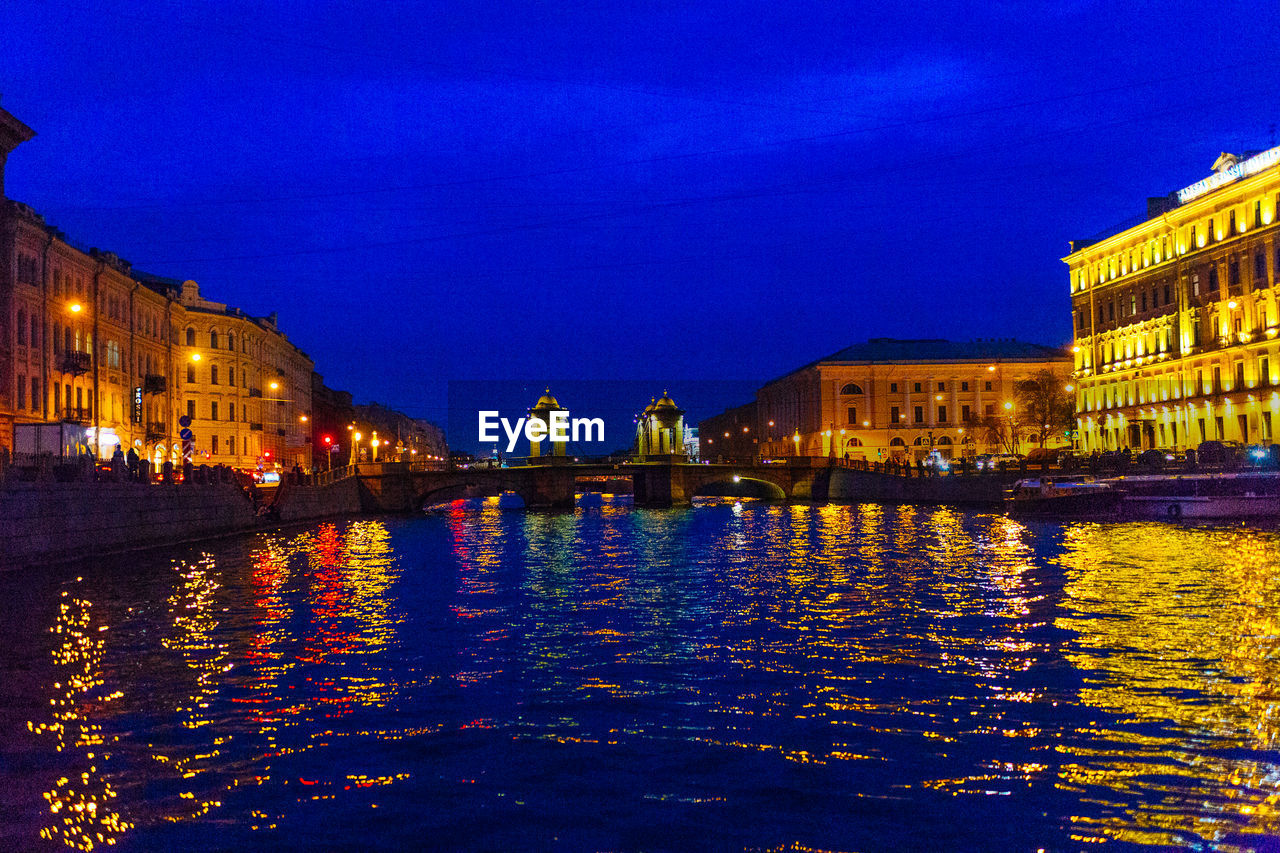 ILLUMINATED BUILDINGS WITH WATERFRONT AT NIGHT