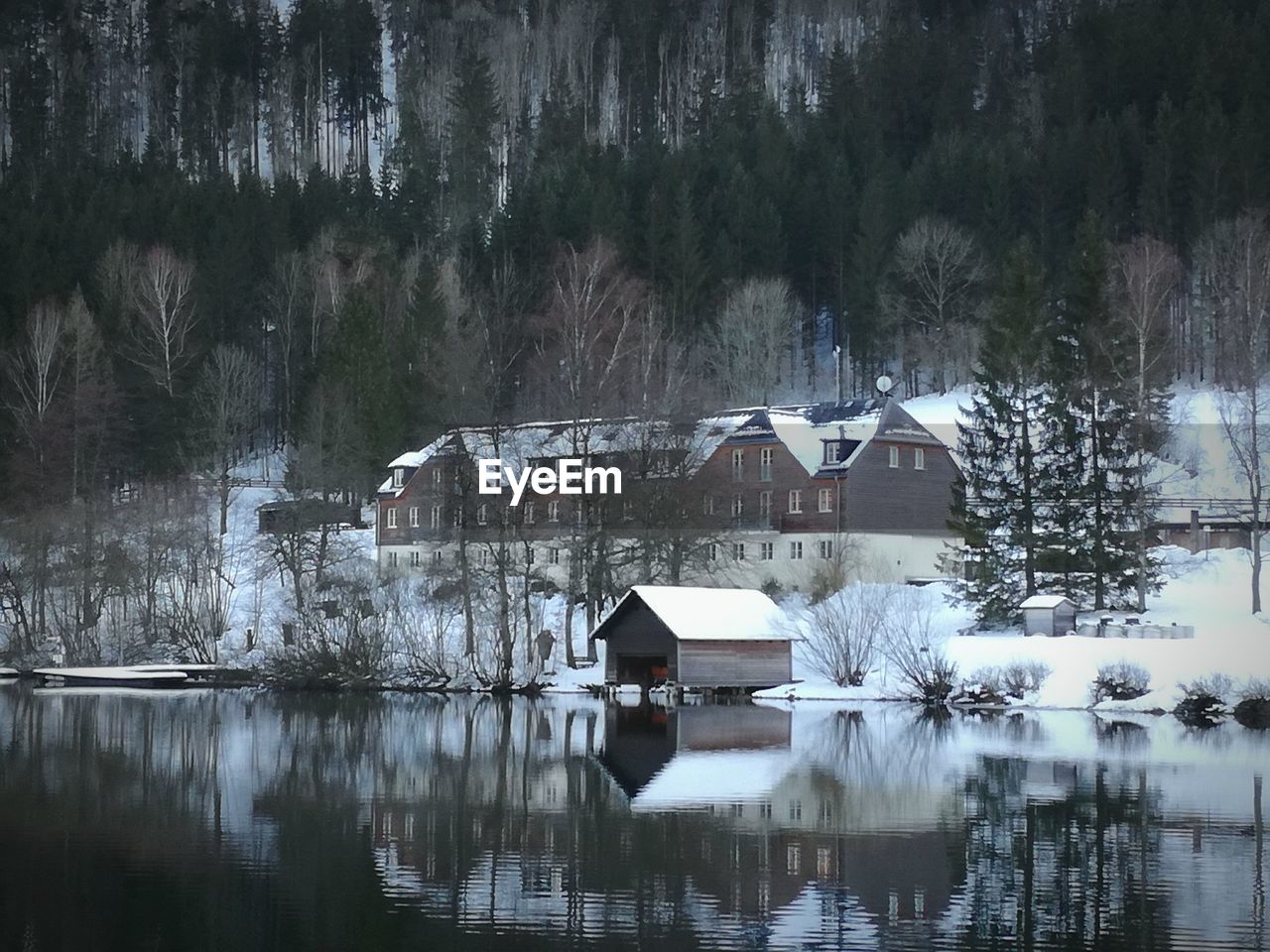 House by lake against sky