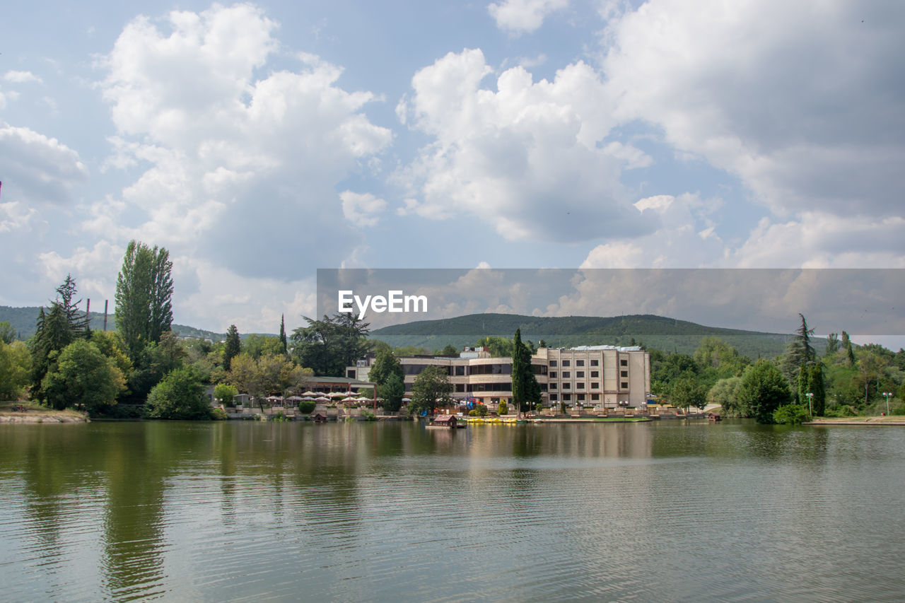 LAKE BY BUILDINGS AGAINST SKY