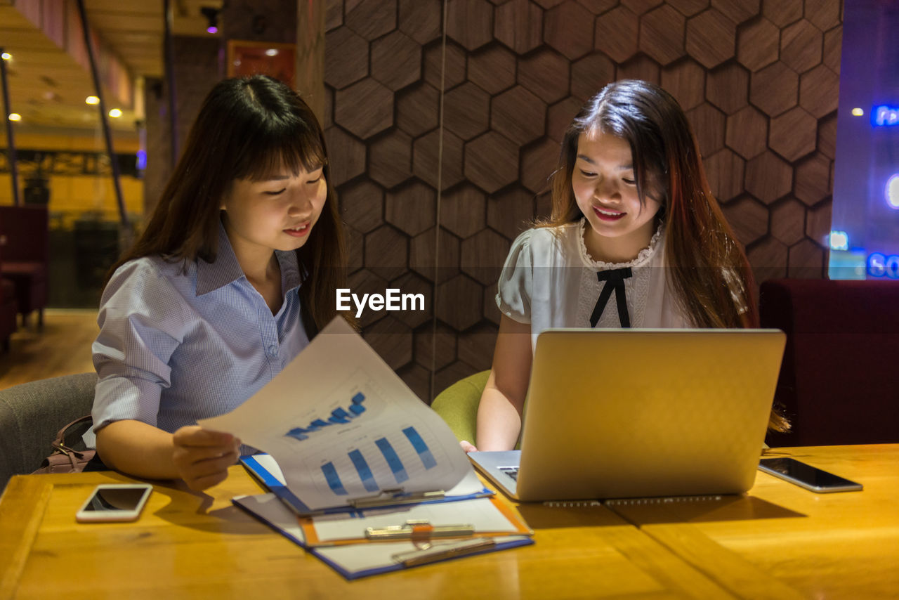 Businesswomen discussing business strategy while sitting in restaurant