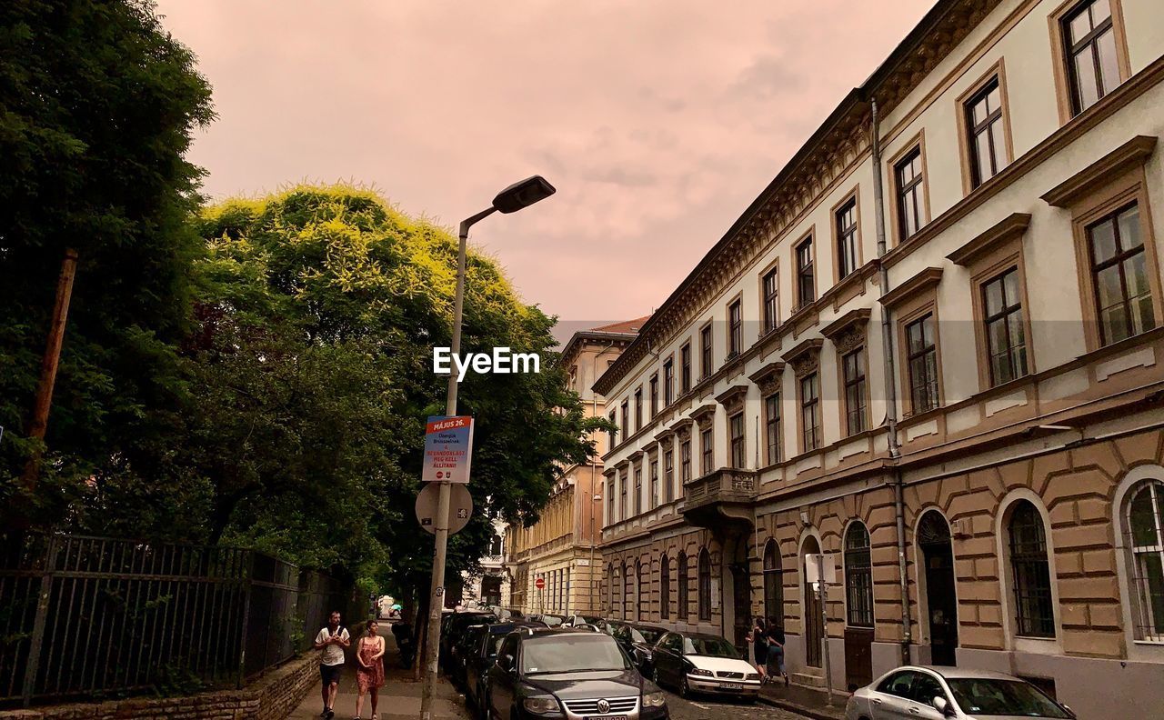 CARS ON STREET AMIDST BUILDINGS AGAINST SKY