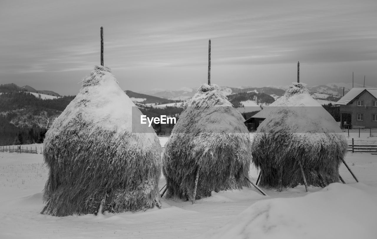 PANORAMIC SHOT OF SNOW COVERED LAND AND BUILDINGS AGAINST SKY