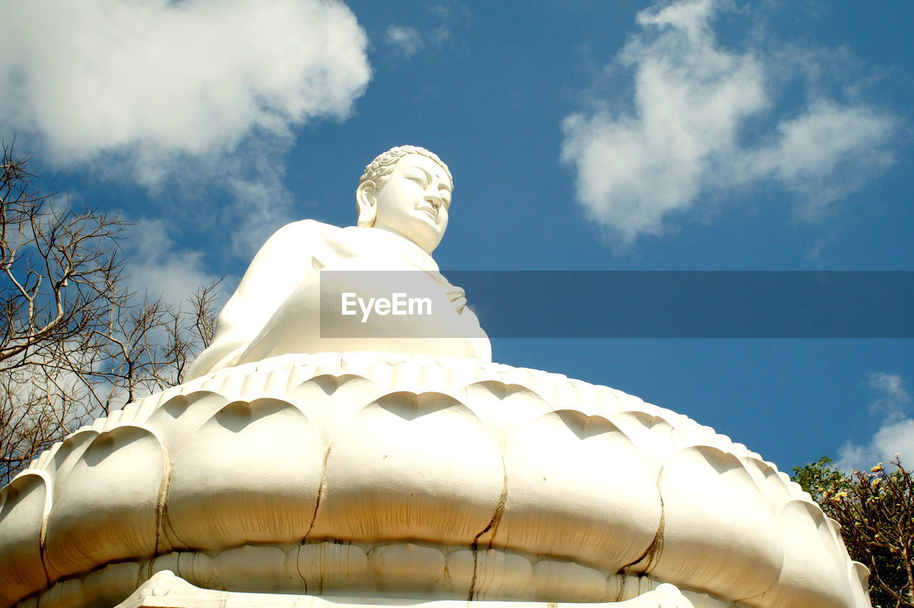 Low angle view of buddha statue against sky