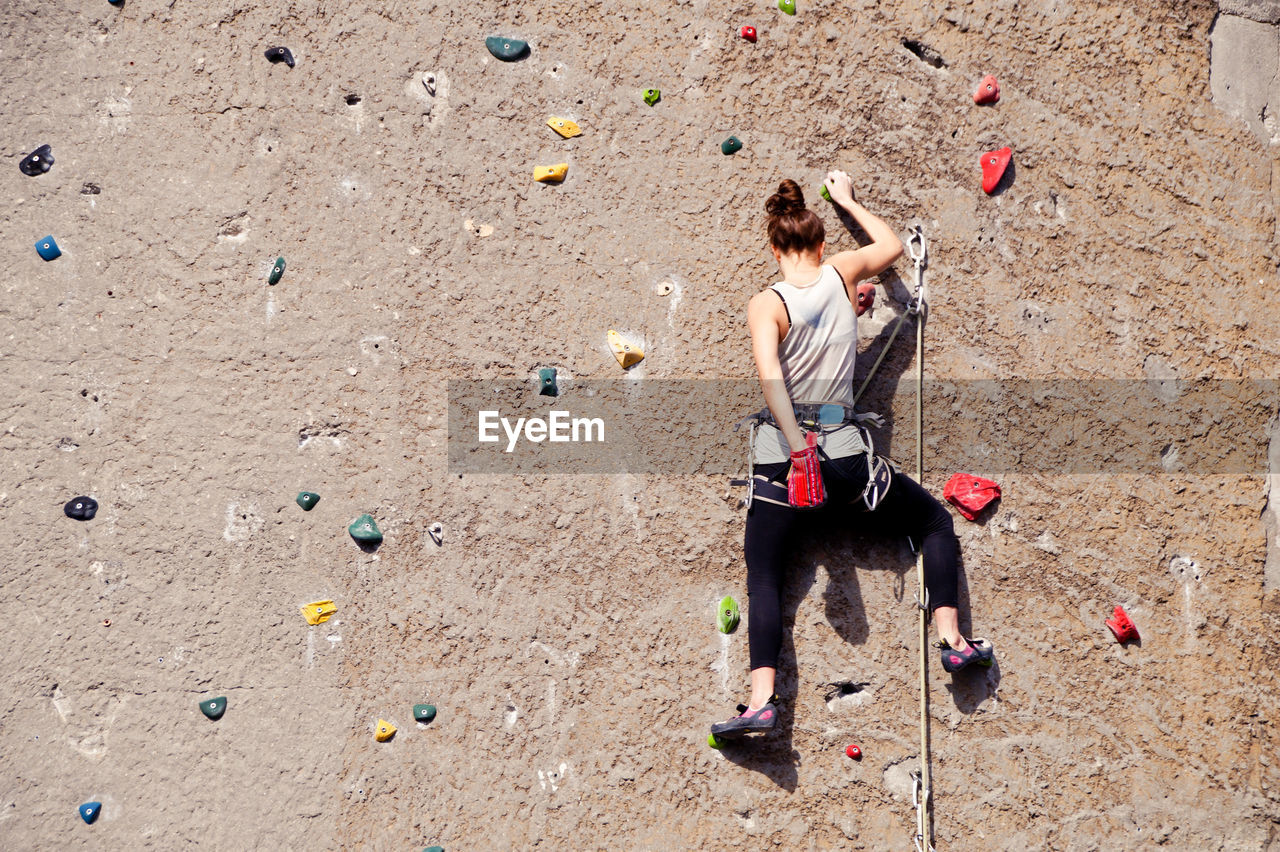 Rear view of woman climbing wall