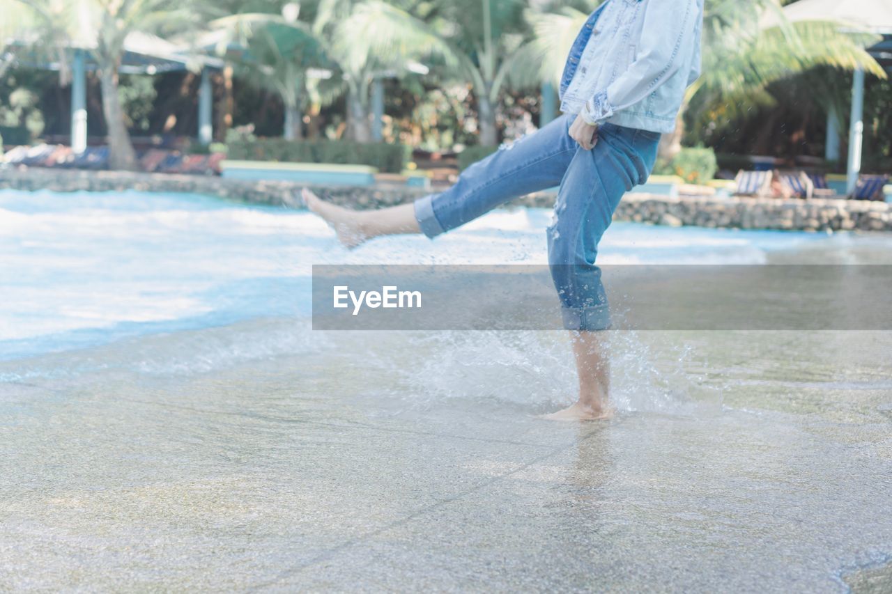 Low section of man splashing water at swimming pool