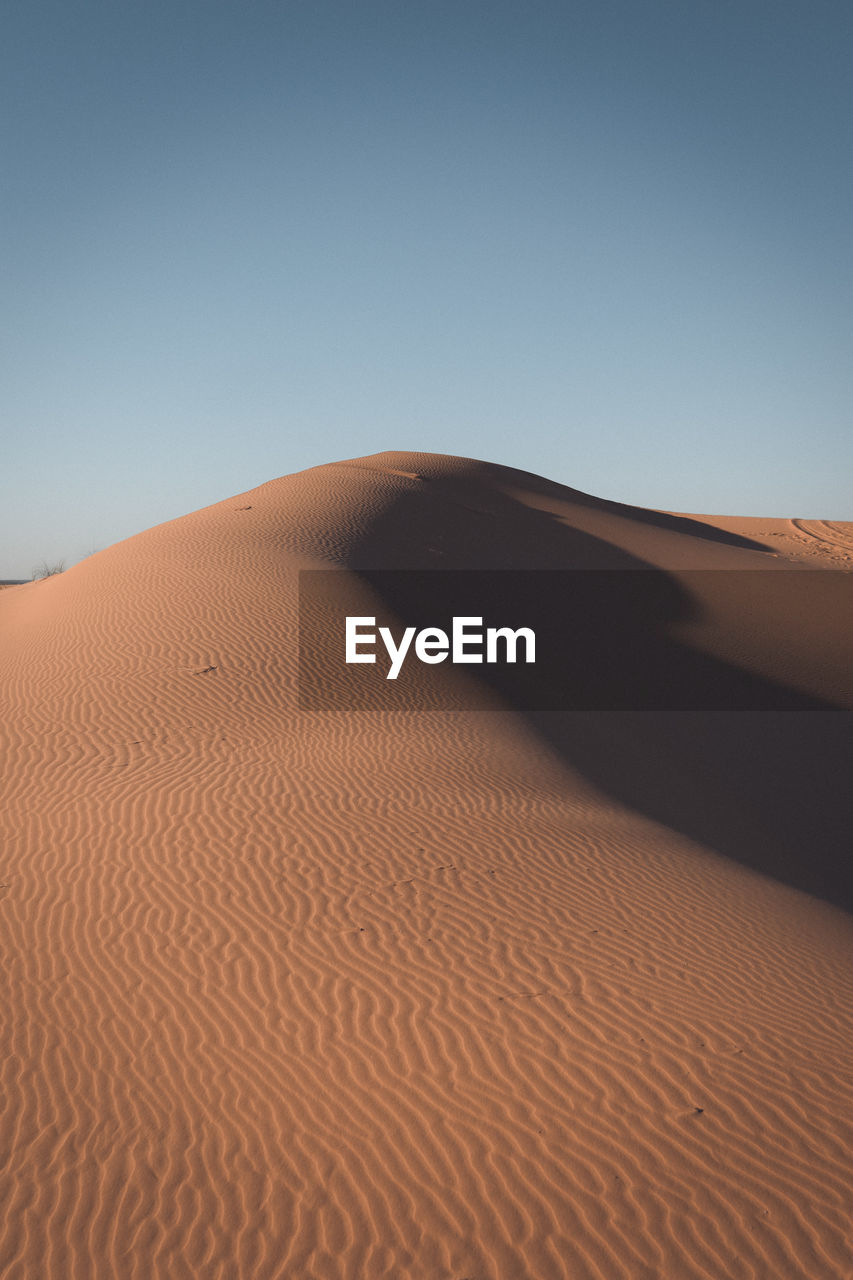 Sand dunes in desert against clear sky