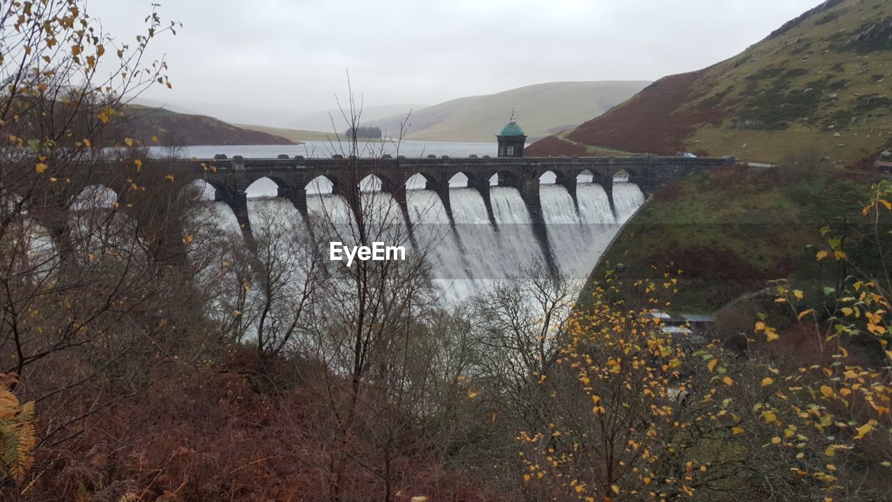 Scenic view of dam and mountains against sky