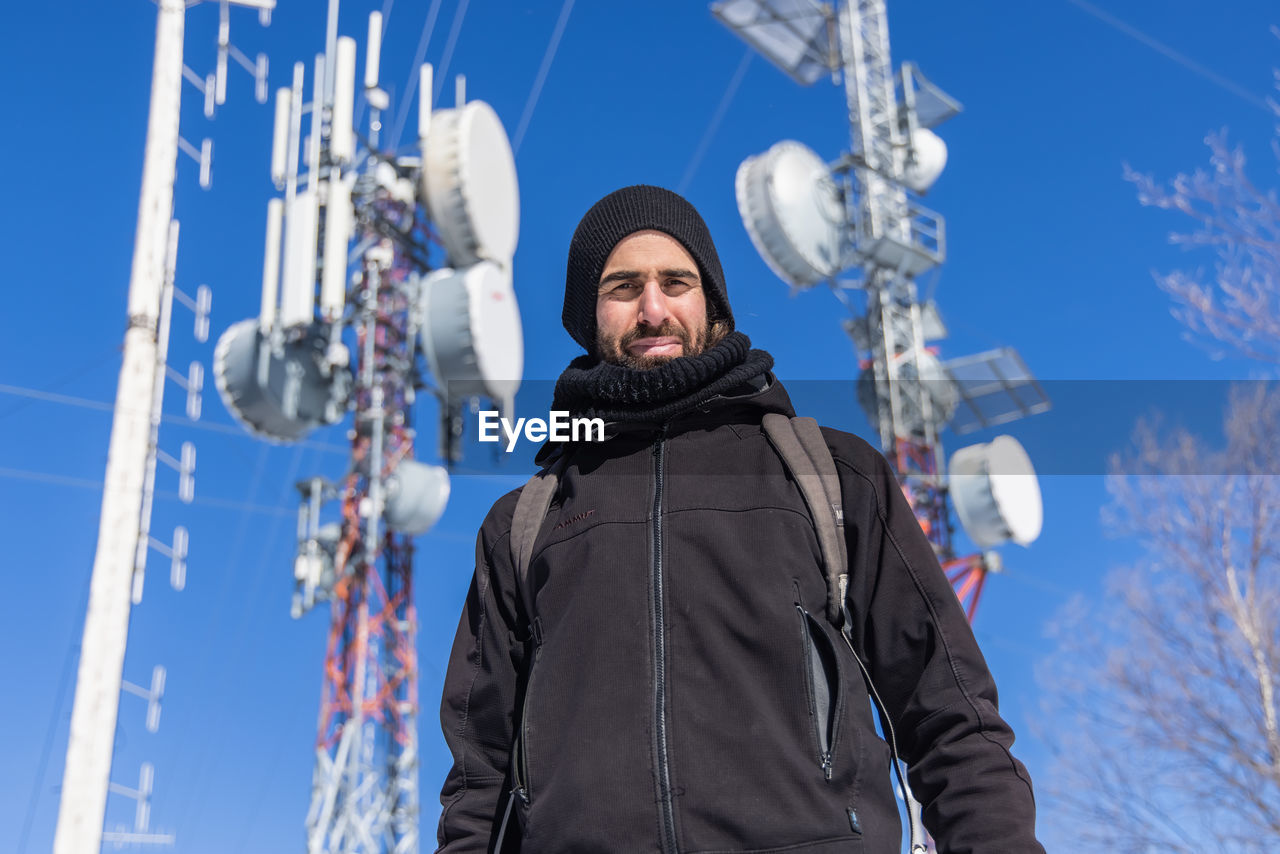 Portrait of young man standing against sky