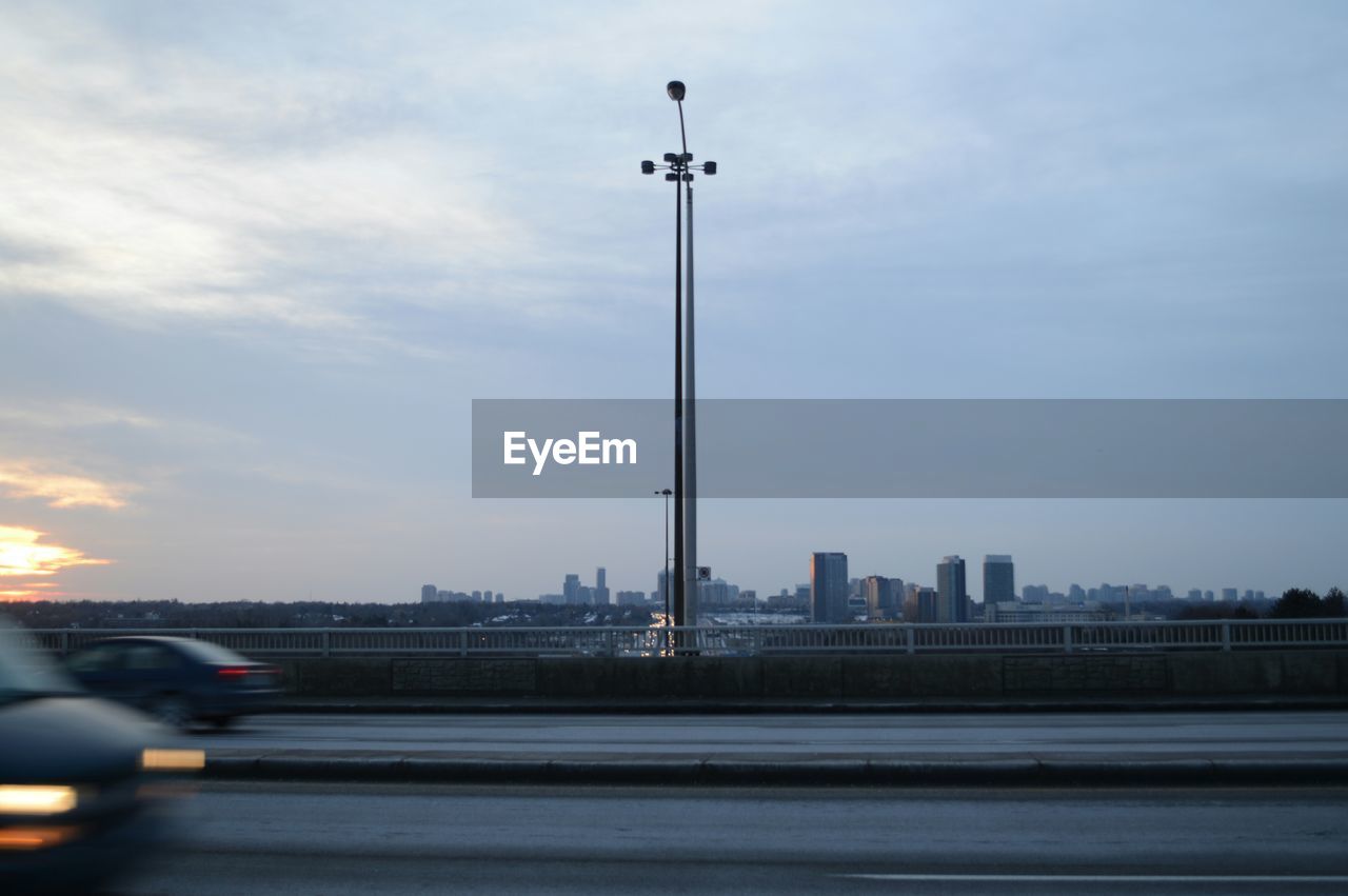 Blurred motion of cars on street against sky at dusk