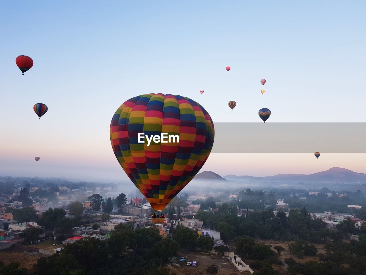 Hot air balloons flying in city against sky