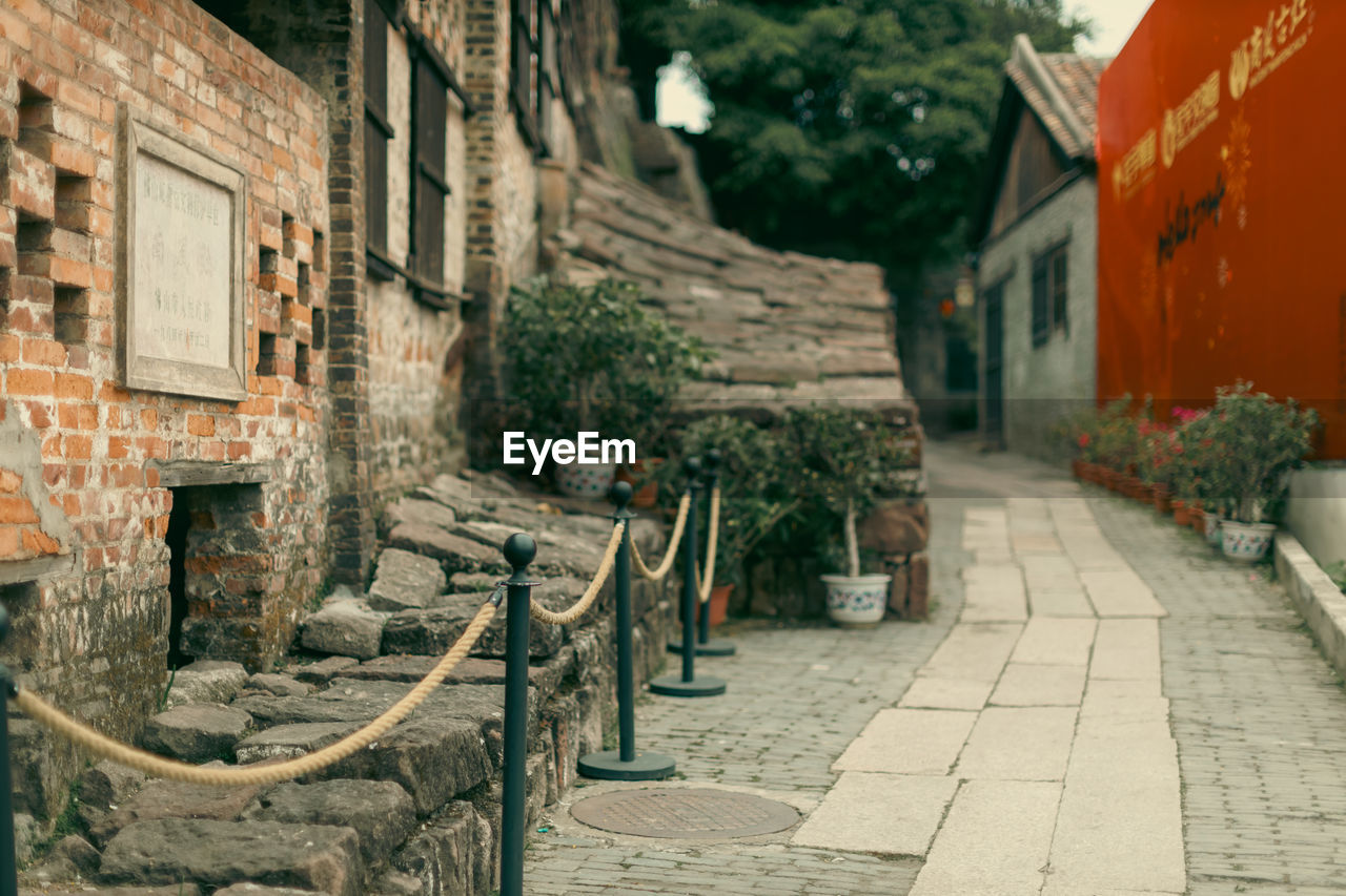 street, architecture, alley, road, town, building exterior, built structure, urban area, city, building, neighbourhood, footpath, plant, infrastructure, nature, courtyard, wall, ancient history, no people, cobblestone, residential district, village, the way forward, outdoors, day, tree, travel destinations, potted plant, old, house, history, flowerpot, sidewalk