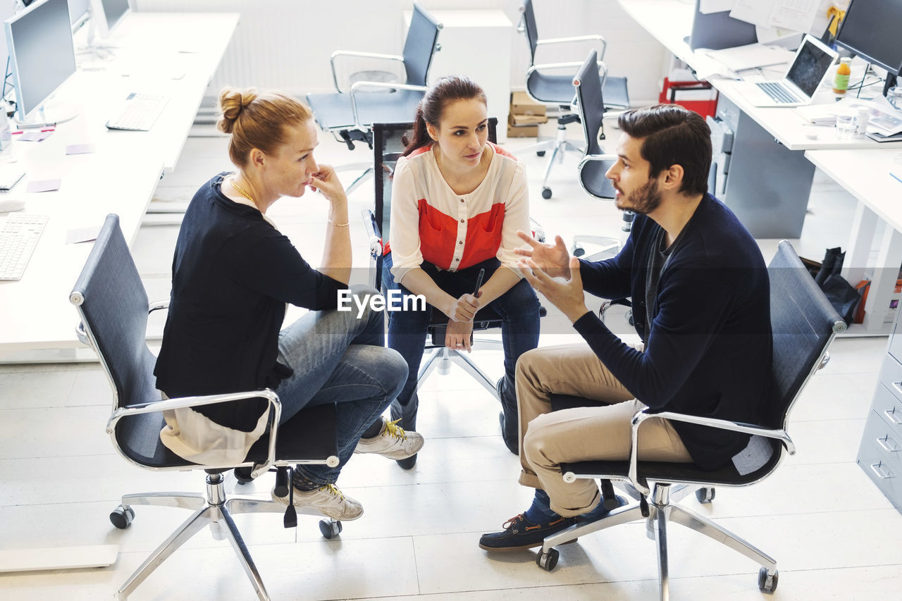 Mid adult businessman with colleagues having discussion in office