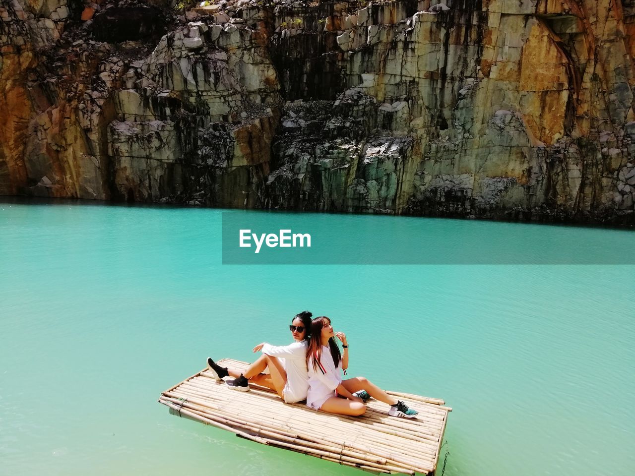 Full length of female friends siting on wooden raft