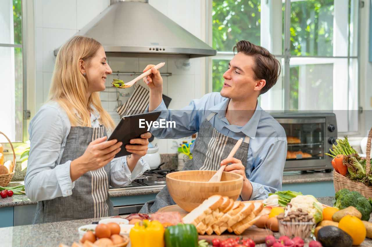 A woman and a man who are lovers are happy to help each other bake.