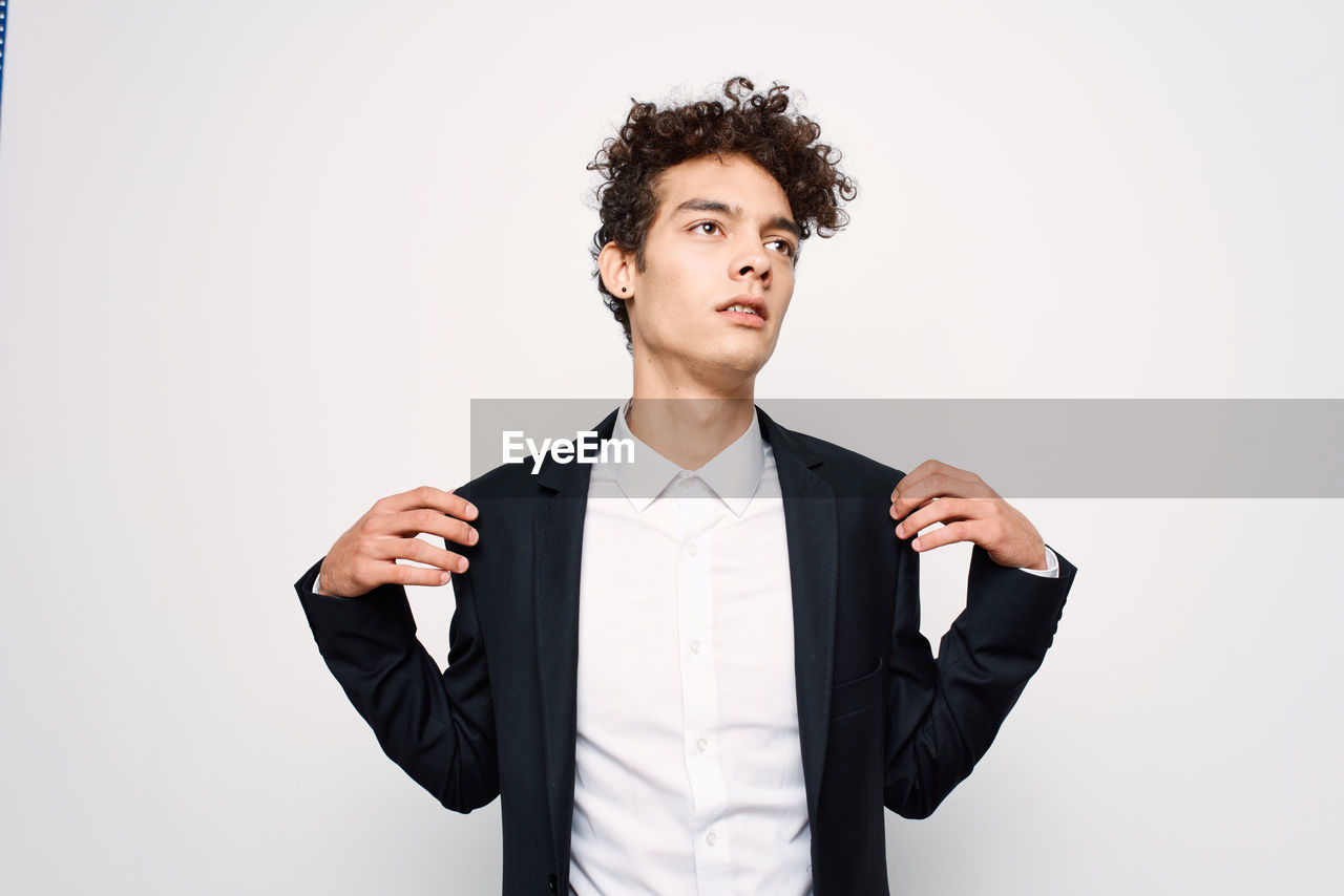 Young man looking away against white background