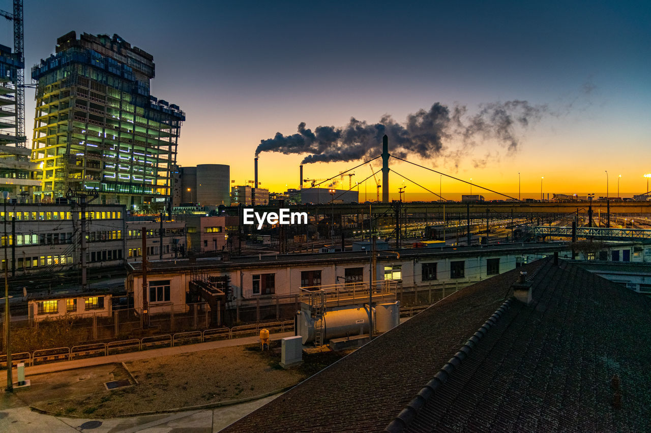 Railroad tracks by buildings against sky during sunset crépuscule paris