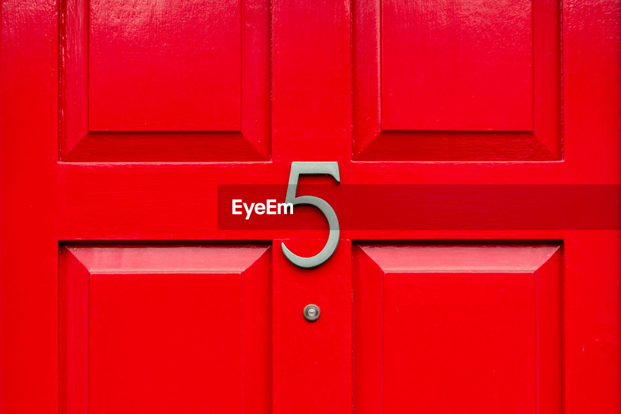 House number 5 on a red wooden front door in london 