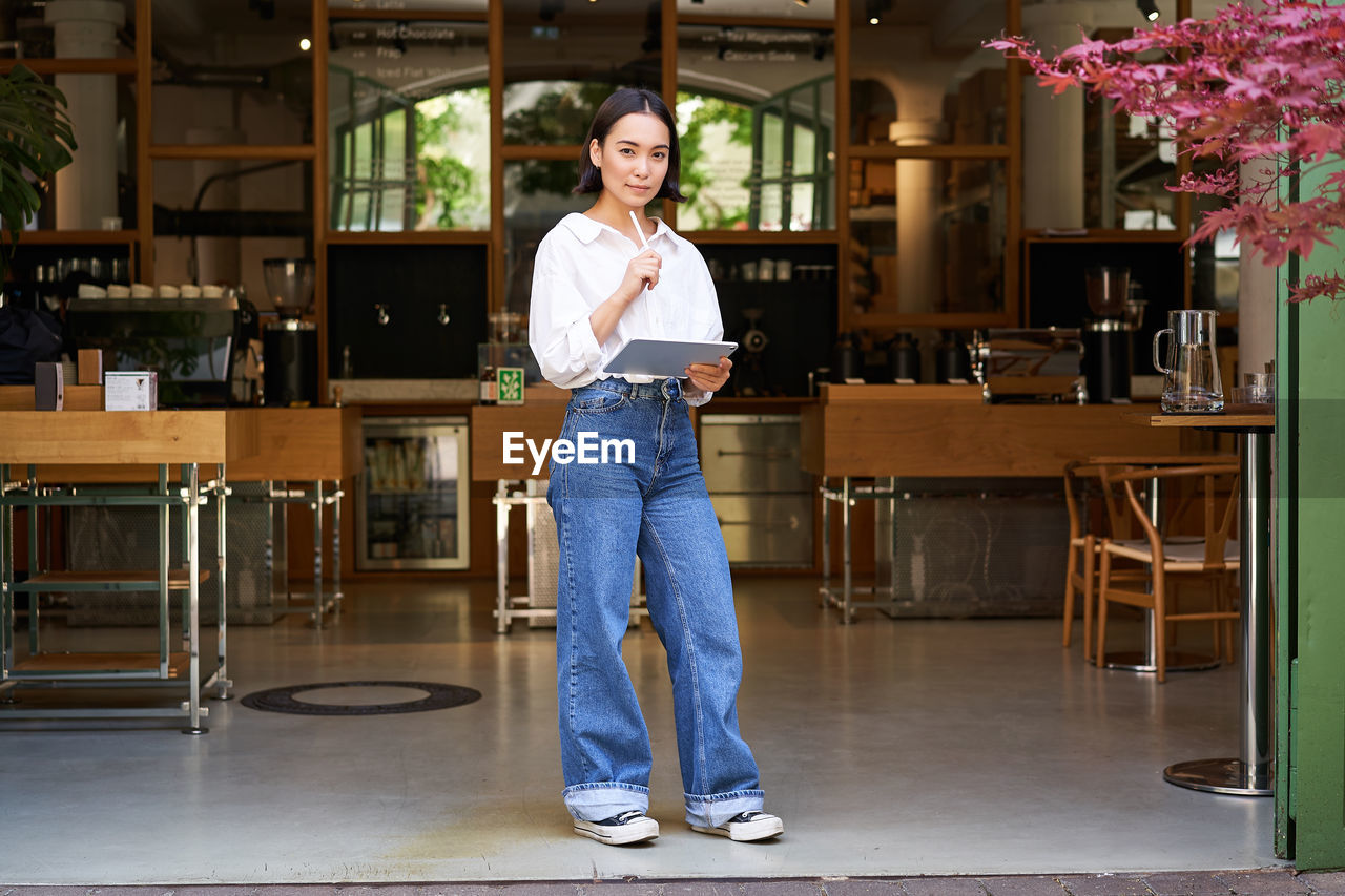 full length of young woman standing in store