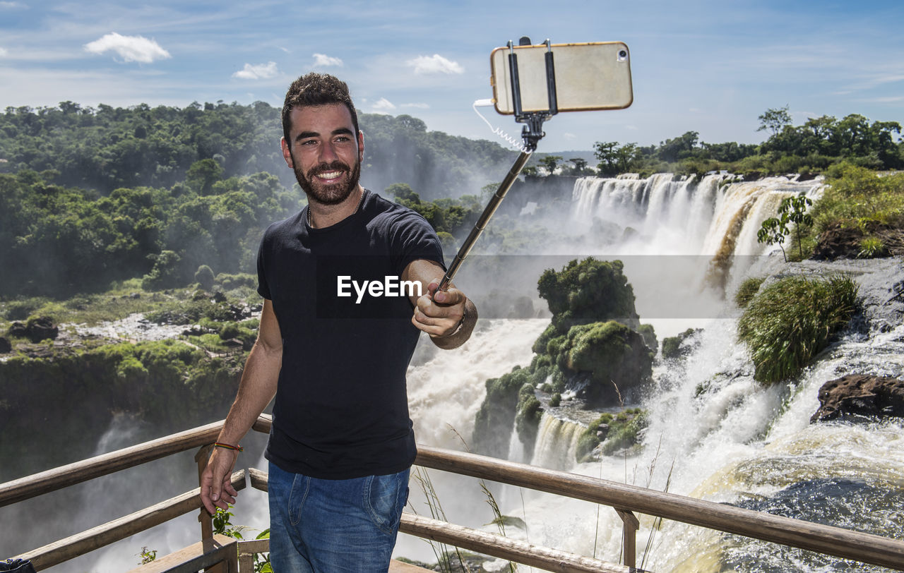 Man taking a selfie with monopod at iguazu waterfalls in argentina