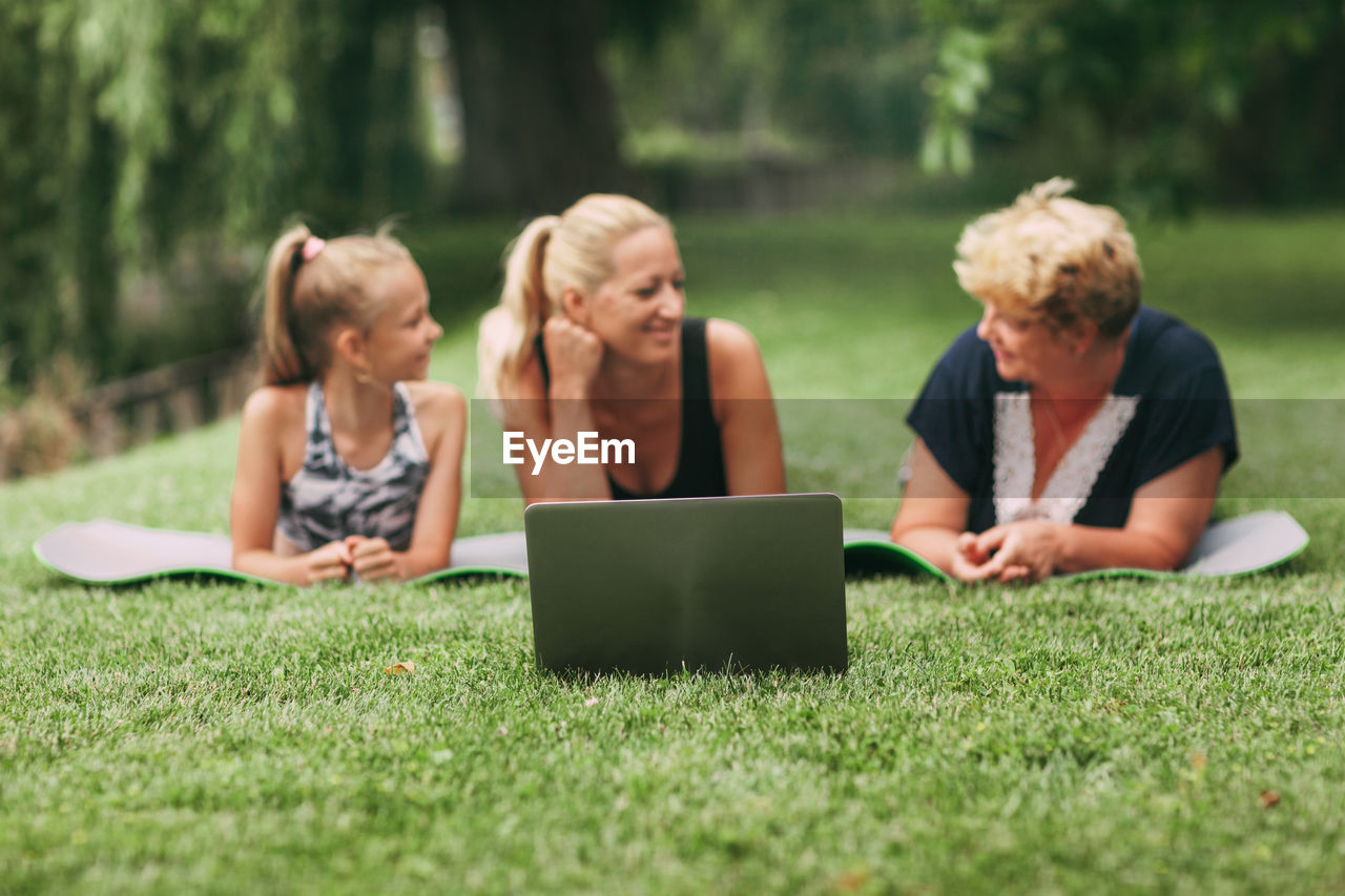 Multi generational family exercising with laptop on grass