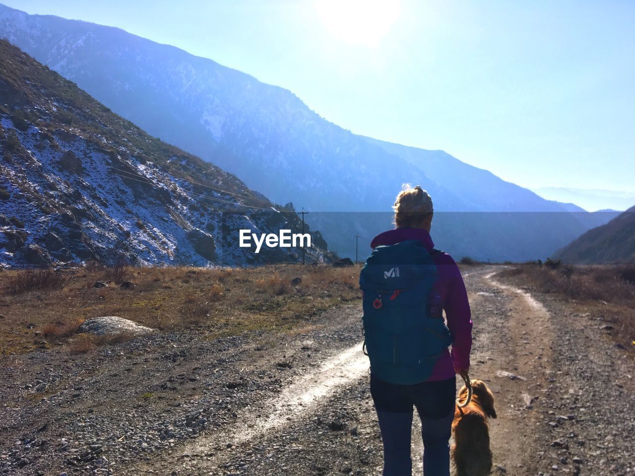 REAR VIEW OF WOMAN STANDING ON MOUNTAIN