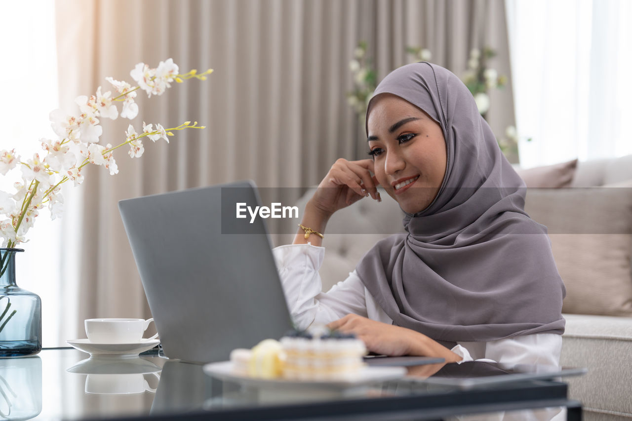 young woman using digital tablet while sitting on table