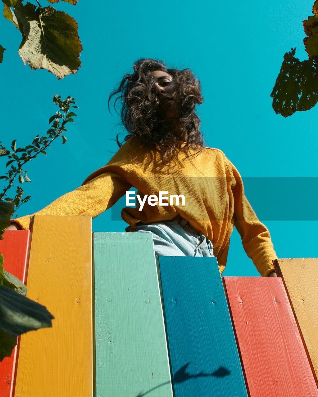 Low angle view of woman standing at colorful fence