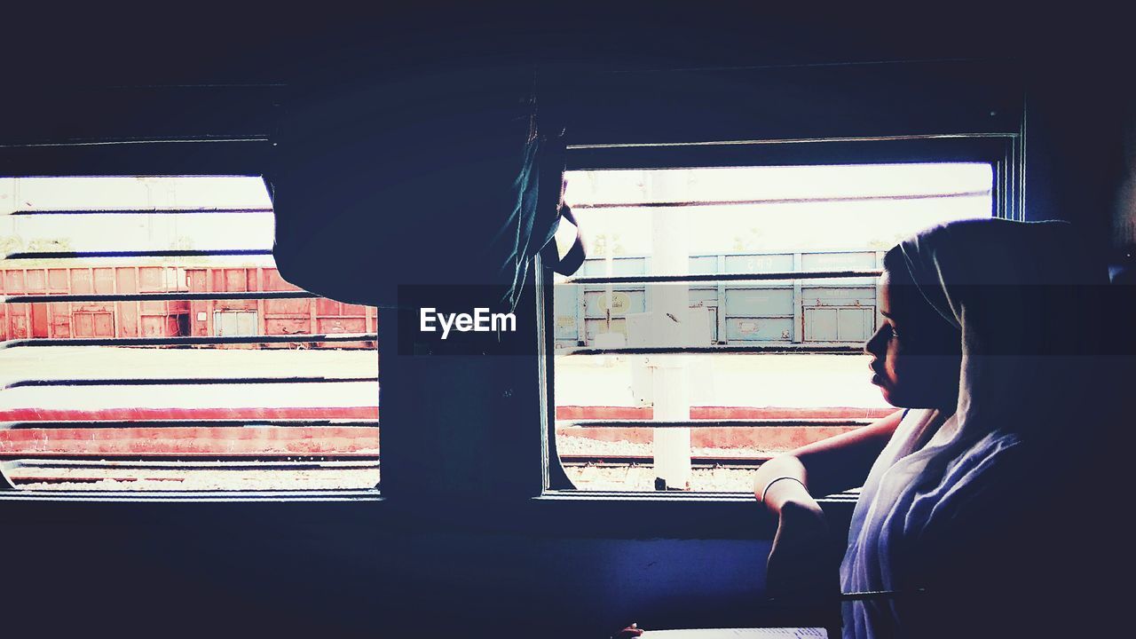 REAR VIEW OF WOMAN SITTING IN TRAIN