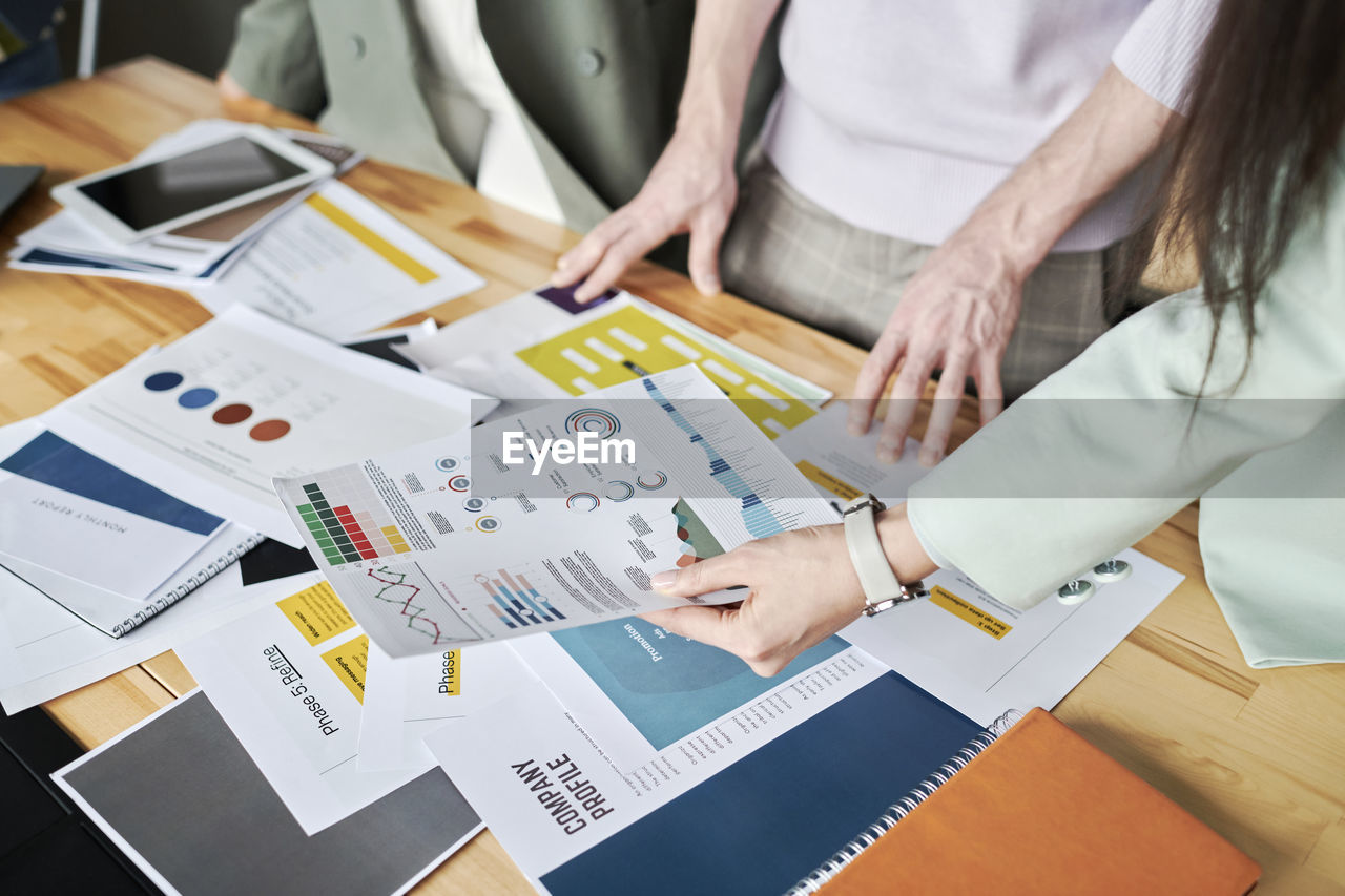 Office colleagues reviewing infographics on desk at office