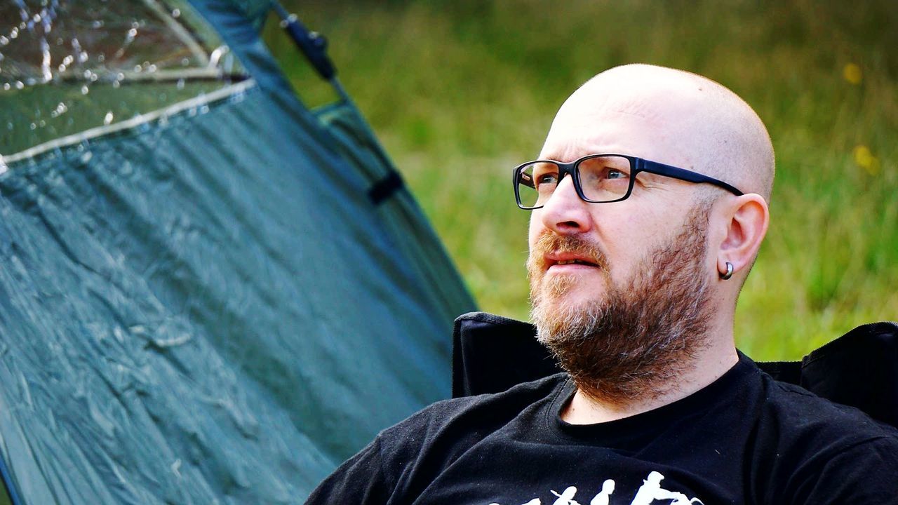 Bearded man with shaved head looking away while sitting outdoors