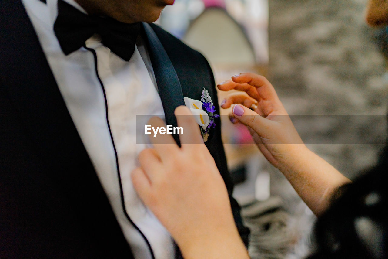 Midsection of woman adjusting groom boutonniere
