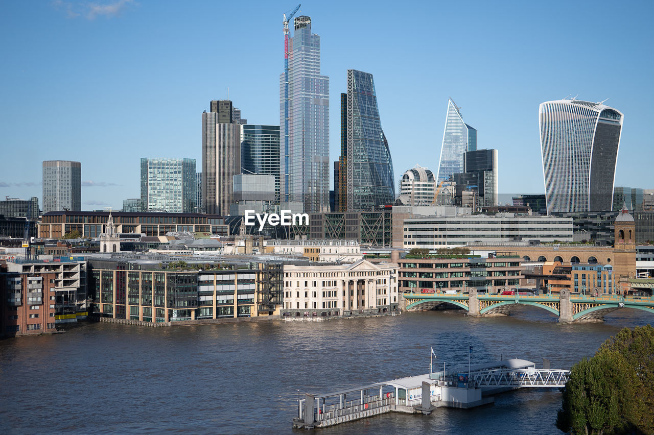 VIEW OF MODERN BUILDINGS BY RIVER AGAINST SKY