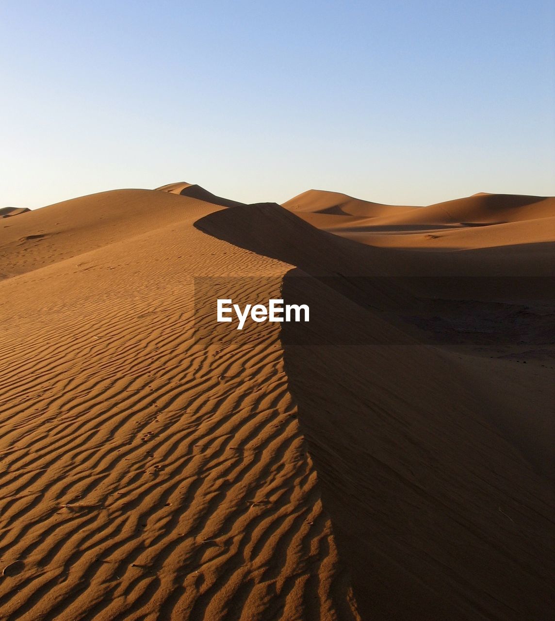 Sand dune in desert against clear sky